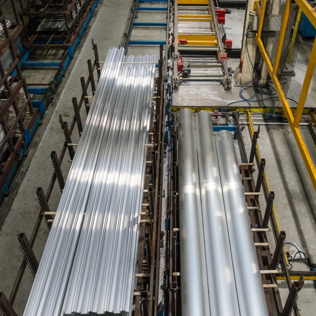 A factory interior showing rows of aluminum or metal sheets on a production line.