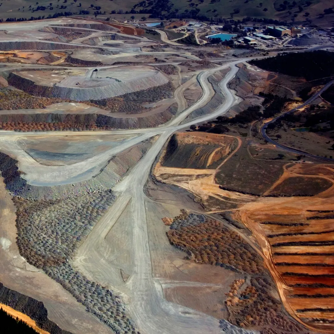 A wide aerial view of a complex mining landscape with winding roads and terraced excavation areas.