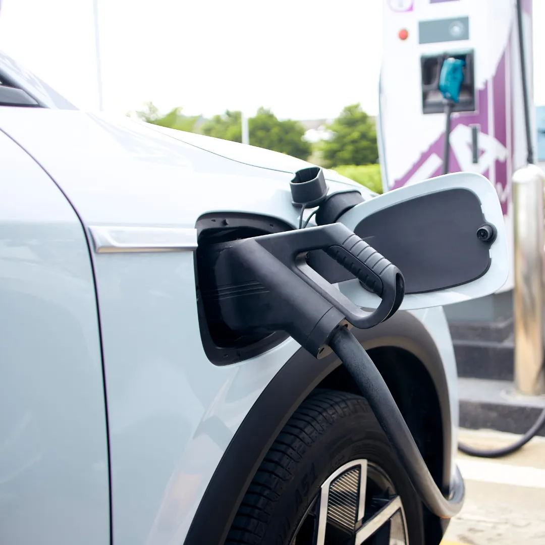 Close-up of an electric vehicle being charged at a charging station.