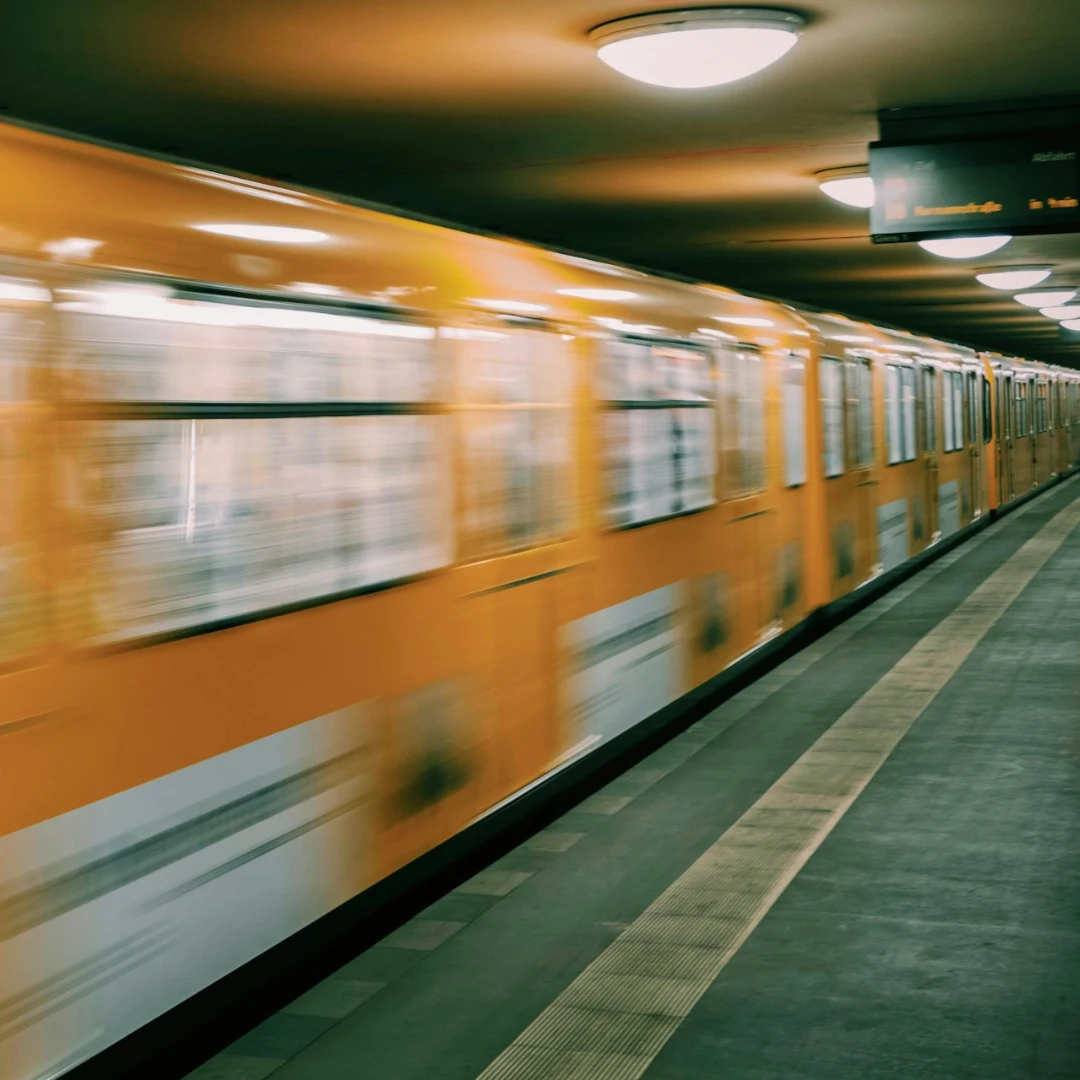 Blurred motion image of a yellow train moving through a station, suggesting speed.