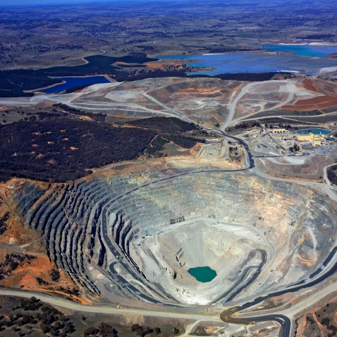 A wide aerial view of an expansive open-pit mining site with terraced layers.
