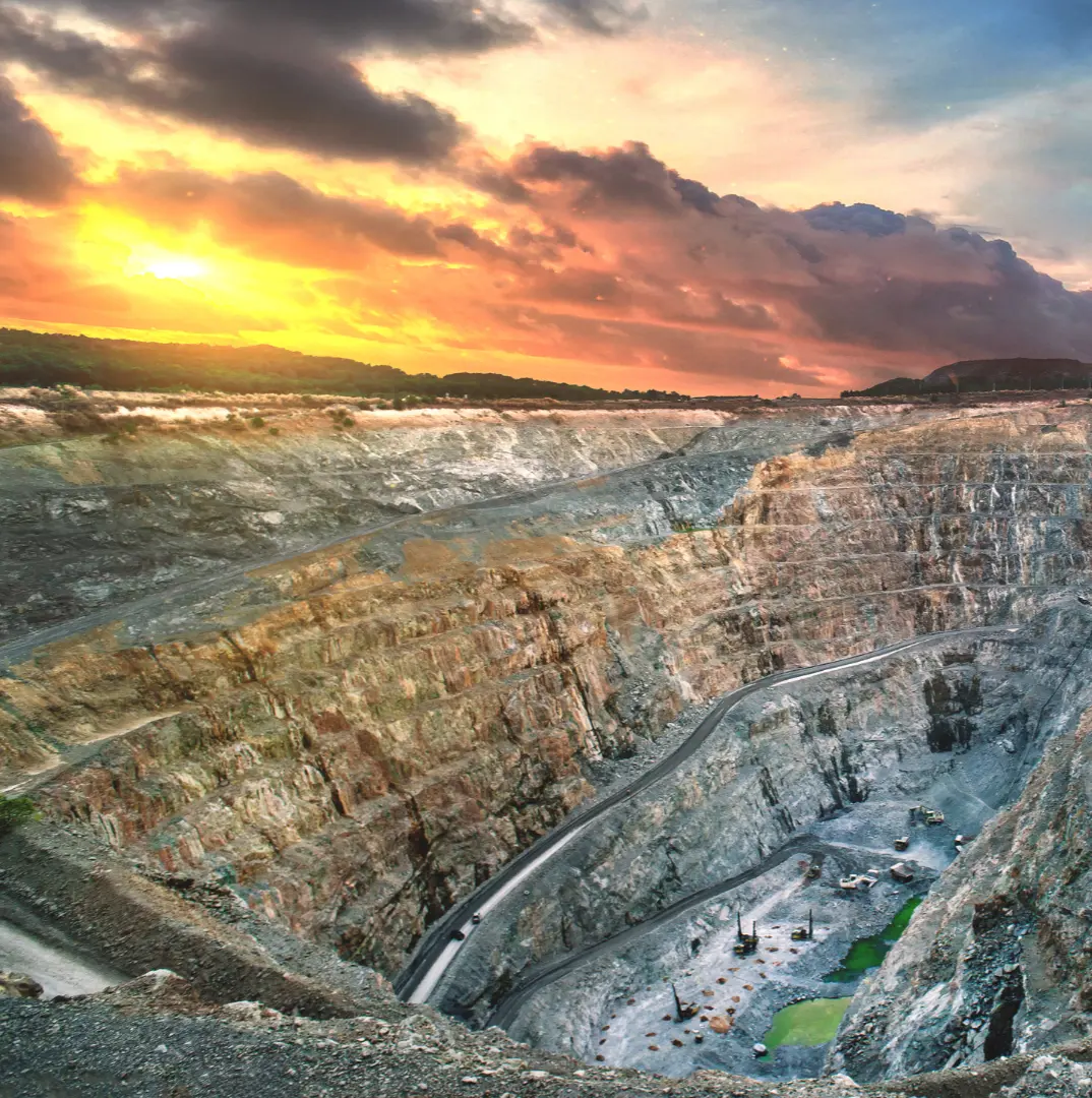 An open-pit mine at sunset, with dramatic clouds in the sky.