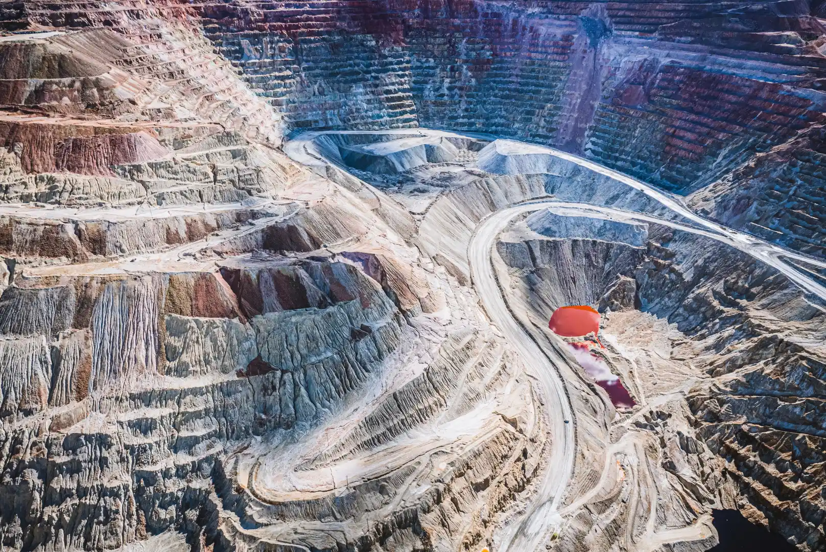 An aerial view of an expansive open-pit mine with terraced layers carved into the earth